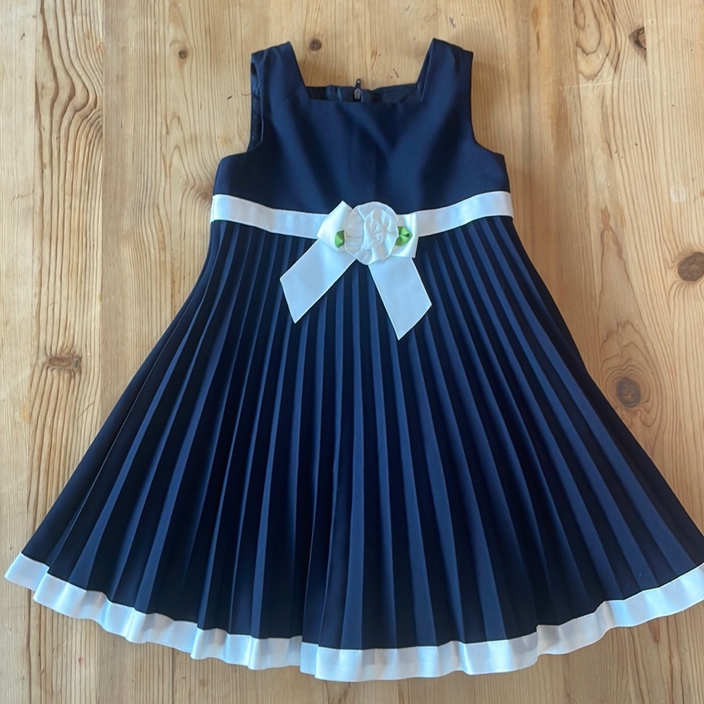 Navy blue pleated dress with white trim.
